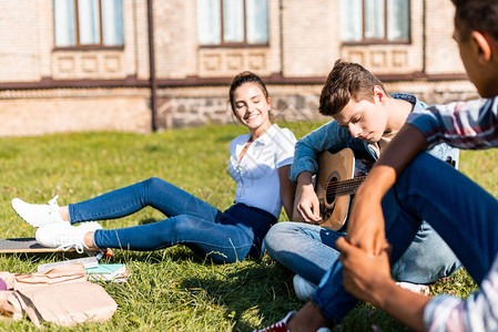 一群快乐的青少年坐在草地上午图片