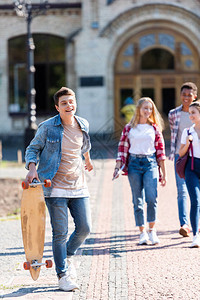 有滑板的少年男孩与朋友一起放学后散步图片