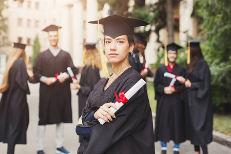 年轻严肃的女人在大学毕业那天与多民族的朋友站在一起教育资图片