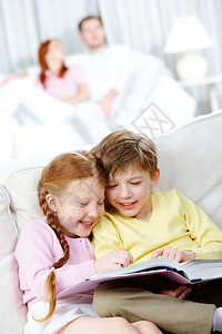 在家坐在沙发上看书的快乐儿童肖像图片