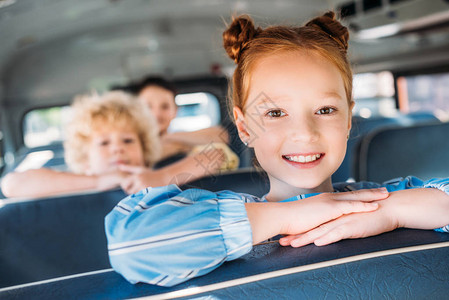 与同学一起坐在校车上的笑着微笑的小女学图片