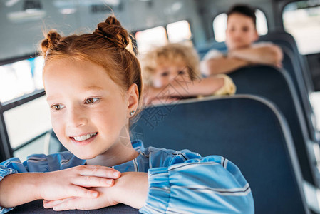 与同学一起坐在校车上的快乐的小女学生近距离肖像图片