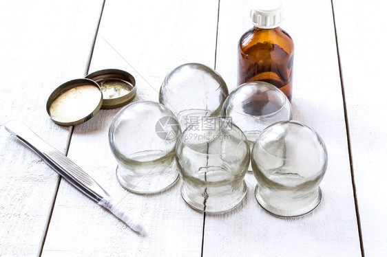 旧的医用杯子泡中的酒精汽油和奶油以及白木制桌面上棉毛的树脂图片