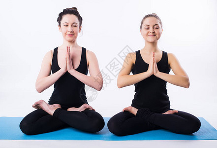 两名妇女做瑜伽和冥想在莲花的位置与图片