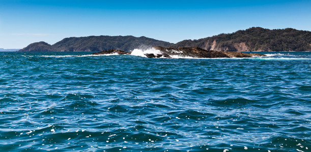 在哥斯达黎加尼科亚湾的水面上浮上一小群危险岩石的海浪冲撞了图片