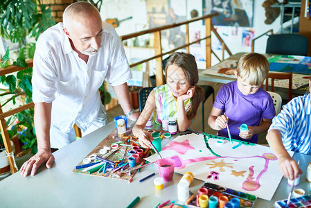 三名儿童在美术课桌边绘画照片的肖像图片