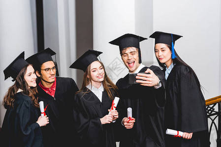 穿着毕业礼服的快乐学生在持有文凭时图片