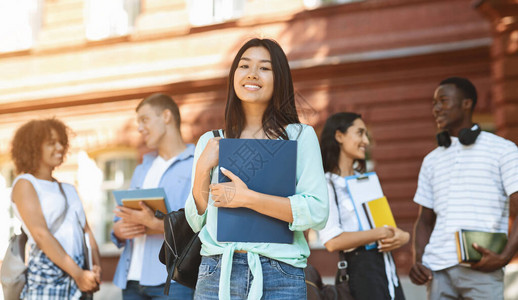 教育概念的贷款快乐的亚洲女学生在校园里与同学和大学楼在户外图片