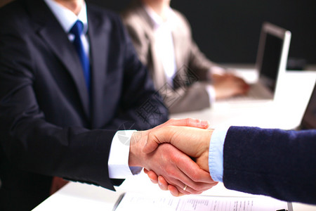 谈判桌握手缔结合同的商务会商图片