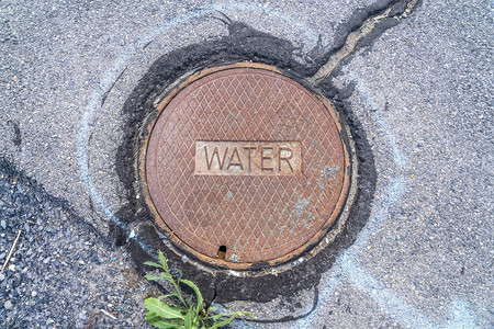 针对道路和岩石地面的可拆卸圆形供水井盖旧的肮脏的和生锈的盘子是通往地下拱顶背景图片