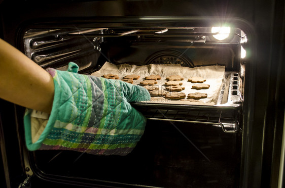 用厨房手套把烤饼干从图片
