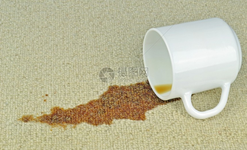 一杯洒在地毯上有污渍的咖啡图片