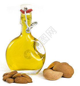 玻璃摇顶瓶中的杏仁油展示了采摘的杏仁背景图片