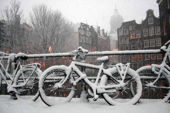 一辆自行车在阿姆斯特丹大楼的暴雪下站着图片