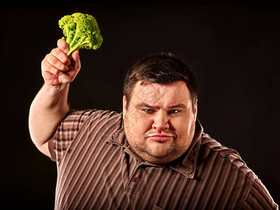 饮食胖子吃健康的食物与蔬菜花椰菜的健康早餐试图的男黑色背景上的概念超图片