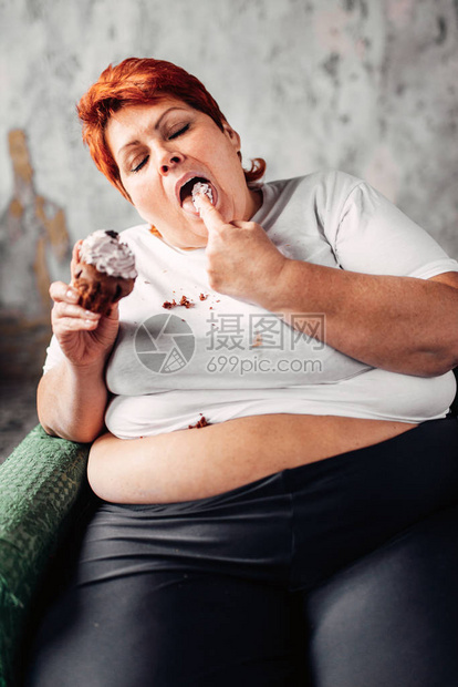 坐在扶椅上吃甜纸蛋糕懒惰肥胖和不健康饮食概念的图片