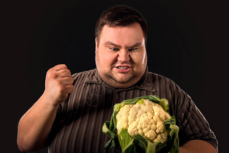 饮食胖子吃健康的食物与蔬菜花椰菜的健康早餐为超重的人男人对低质量的图片