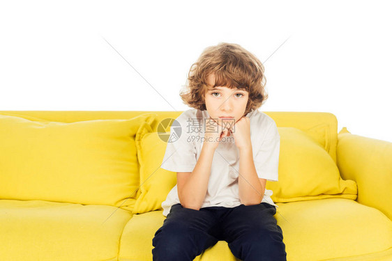 坐在黄色沙发上靠着巴掌躺着的不高兴的男孩图片