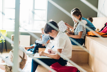 年轻男学生与同学一起坐在学校的Trune上书写图片