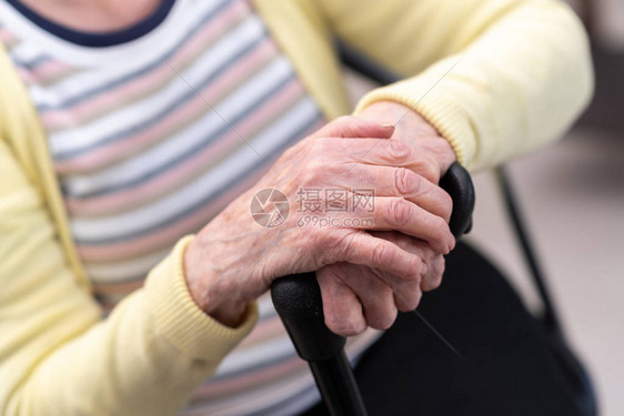 老妇人双手拄着拐杖坐着图片