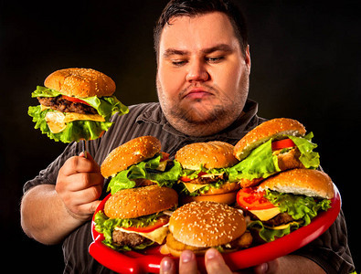 胖子吃快餐汉堡包超重者的早餐垃圾餐会导致肥胖人经常在黑色背图片