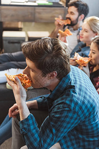 年轻人坐在沙发上吃披萨图片