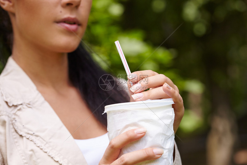 在绿色背景上喝饮料的女人高清图片下载-正版图片502632074-摄图网