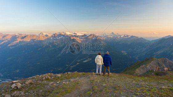 情侣手拉观看日落时阿尔卑斯山的壮丽全景图片