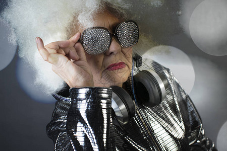 一个惊人的祖母DJ带耳机的老太在迪斯图片