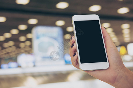 在机场站立和等待行李报销申请时手持和使用白色手机黑屏空白黑屏幕的混装图图片