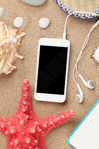 带海星和贝壳的海沙上的智能手机带有复制空图片