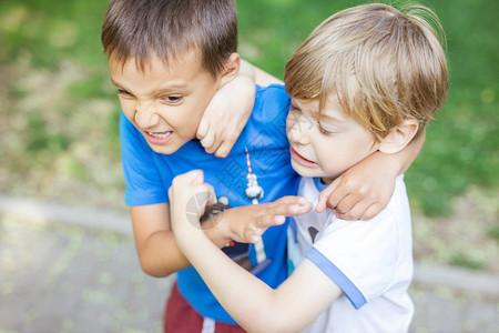 两个男孩在户外打斗朋友在夏日公园摔跤图片