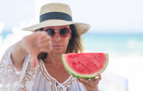 中年黑发女人在海边吃西瓜时图片