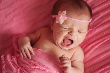 一名身着粉色花头带的8天大打哈欠女婴的高视线图片