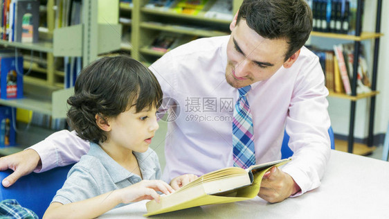 老师和男孩学生用书架背景的书学习图片