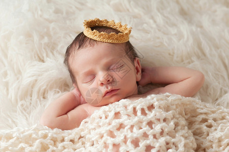 一名12天大的身戴金冠的新生儿男孩的肖像他睡在米格罗卡蒂地毯上图片
