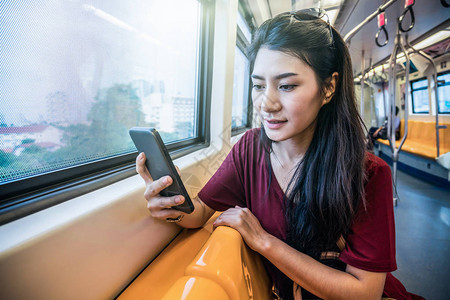 在地铁使用智能手机的亚洲女乘客在大城市旅行时搭乘便衣图片