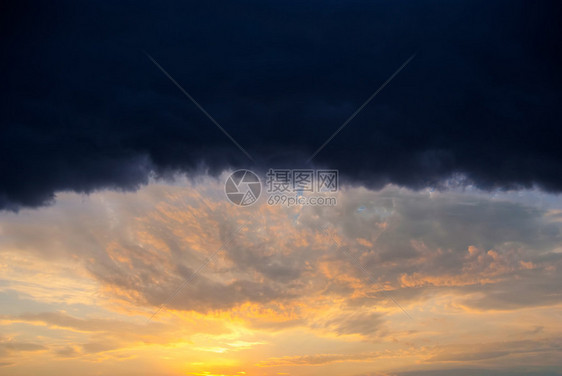 巨大的雨云照亮了橙色的夕阳图片