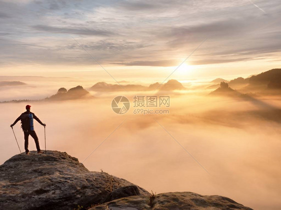 手持带杆子的木轮阳光春夏和导游留在山尖悬崖上在迷雾谷上空的岩石观察点图片