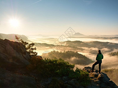 男子剪影停留在锋利的岩峰上满足徒步旅行者欣赏美景岩石峭壁的高个子观看下来风景生动而强图片