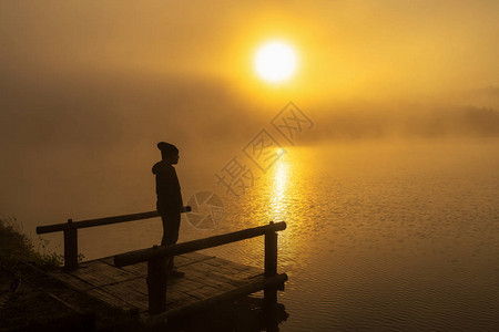 日出时分站在船屋河湖上的剪影抑郁男子图片