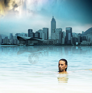 人漂浮在水中在未来的城市和戏剧天空的图片