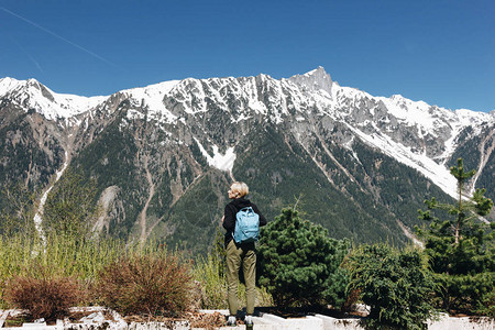 背着面的年轻女子背着包站在高山雪峰上蒙特图片