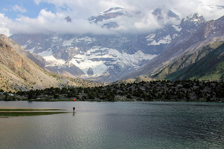孤单的人站在湖边和美丽的风景上有着惊人的雪冠山峰塔吉克斯坦图片