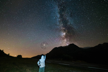 一个人在阿尔卑斯山的高海拔看星空和银河火星行在左边夏季图片