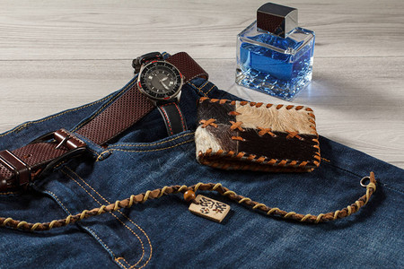 男士香水带皮的手表带皮的蓝色牛仔裤皮革钱包和灰色木质背图片