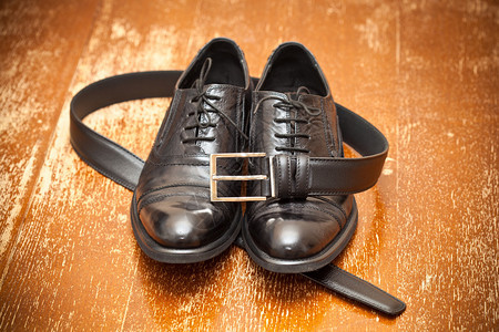 经典黑色皮鞋和复古背景上带扣的皮带图片