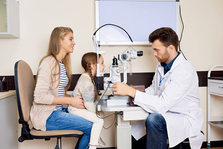 在眼科诊所进行体检时使用割光灯微笑的小女孩的眼部观察器测试图片