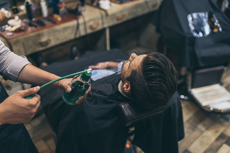 理发师在理发店向顾客涂抹香水的裁剪图像图片