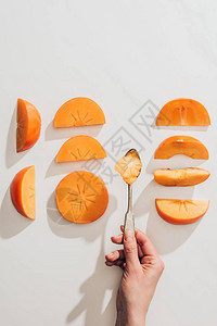 将勺子压在persimmon碎片之上的妇图片